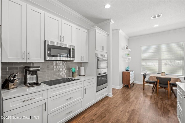 6910 Hundred Acre Dr, Cocoa, FL 32927 - kitchen featuring appliances with stainless steel finishes, light countertops, white cabinetry, tasteful backsplash, and ornamental molding