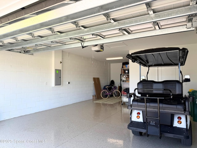 garage featuring concrete block wall, a garage door opener, and electric panel