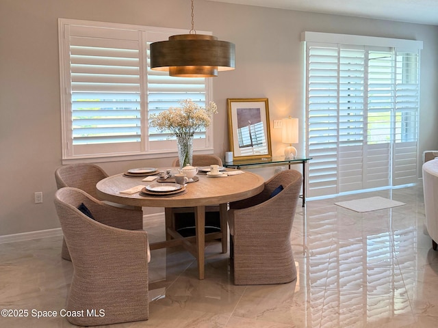 dining space with marble finish floor and baseboards