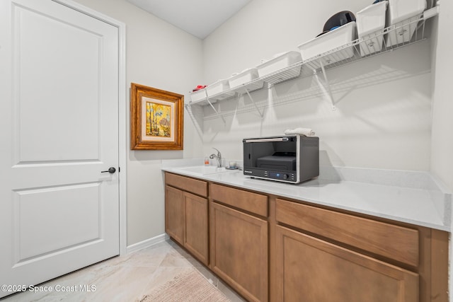 8811 Stormy Sky Ct, Melbourne, FL 32940 - bar featuring a sink, light marble finish flooring, and baseboards