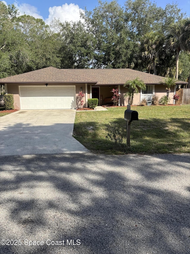 ranch-style home with stucco siding, driveway, a front yard, and a garage