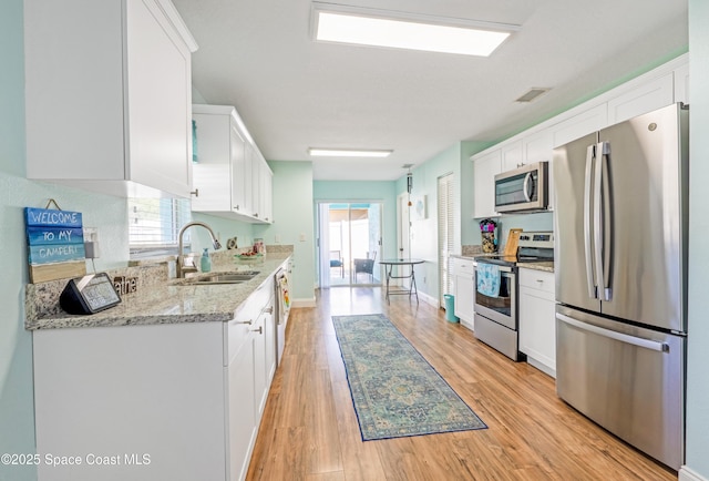 kitchen featuring a sink, light wood-type flooring, white cabinets, appliances with stainless steel finishes, and visible vents