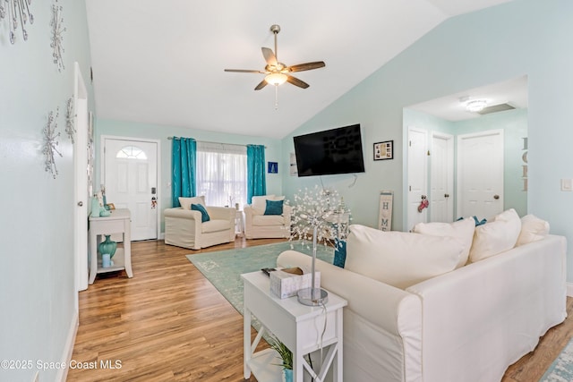 living room featuring ceiling fan, lofted ceiling, light wood-style floors, and baseboards