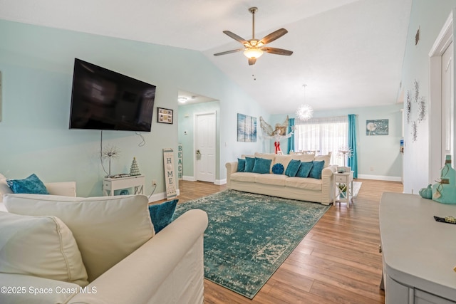 living room featuring baseboards, a ceiling fan, light wood-style floors, and lofted ceiling