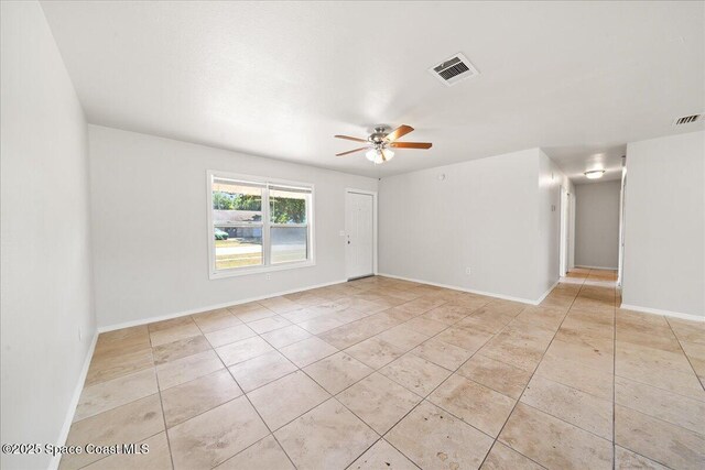 spare room featuring ceiling fan, light tile patterned floors, and baseboards
