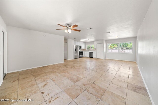 unfurnished living room featuring a ceiling fan, baseboards, and light tile patterned floors
