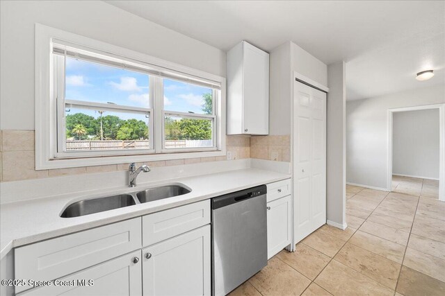 kitchen with dishwasher, a sink, white cabinets, light countertops, and baseboards