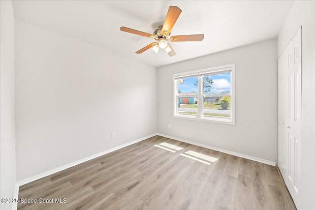 empty room featuring light wood-style flooring, baseboards, and a ceiling fan