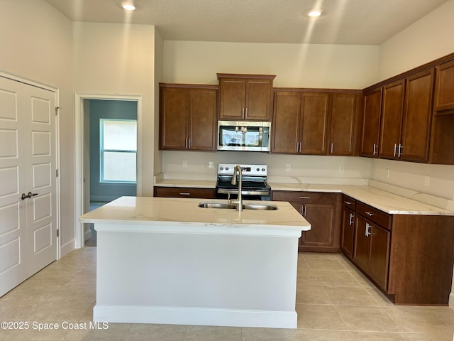 1208 Soleway Ave NW, Palm Bay, FL 32907 - kitchen with stainless steel appliances, light tile patterned floors, light stone countertops, and a kitchen island with sink