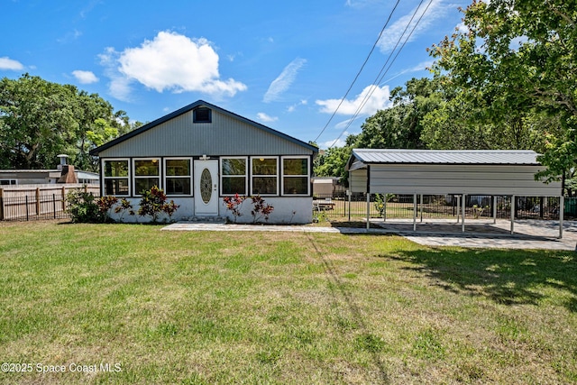 rear view of house featuring a detached carport, fence, and a yard
