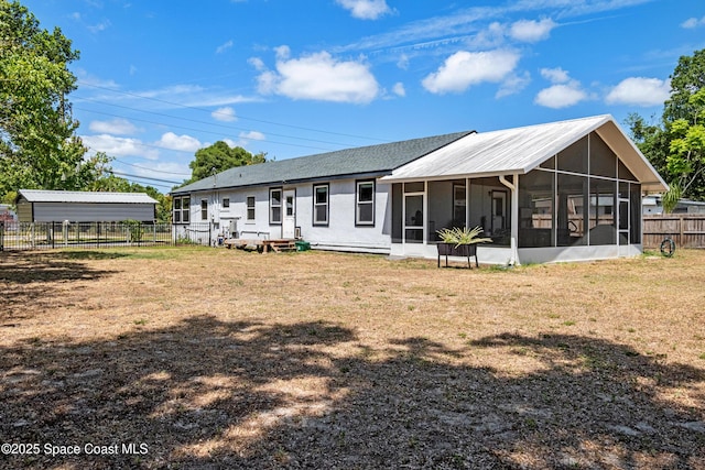 back of property featuring a sunroom, a detached carport, fence, and a yard