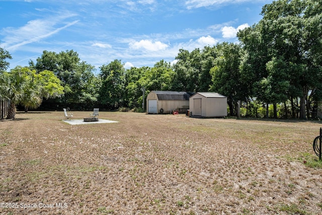 view of yard featuring a storage shed, a patio, an outdoor structure, and an outdoor fire pit