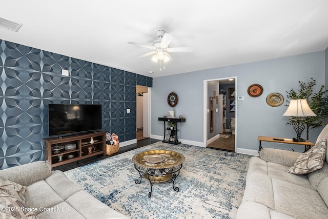 living room featuring visible vents, an accent wall, baseboards, wallpapered walls, and a ceiling fan