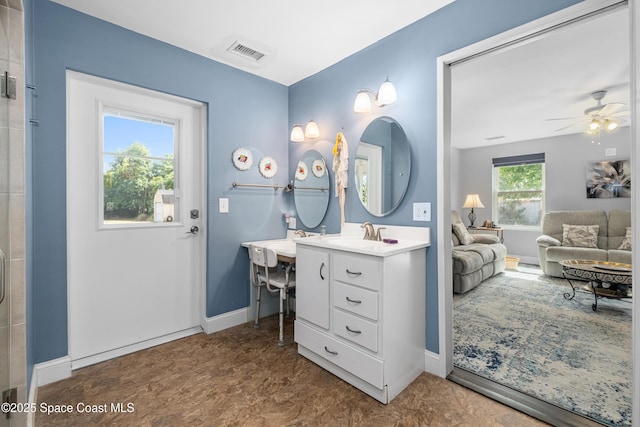 full bathroom featuring ceiling fan, a shower with shower door, vanity, baseboards, and visible vents