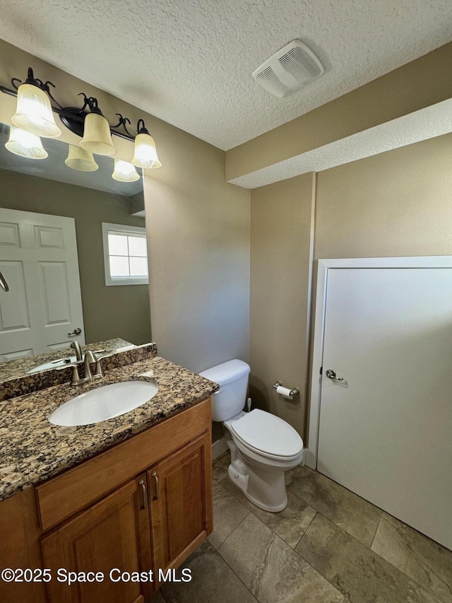 bathroom featuring toilet, vanity, a textured ceiling, and visible vents
