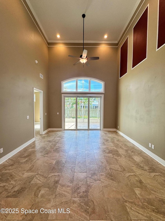 empty room featuring a ceiling fan, baseboards, and ornamental molding