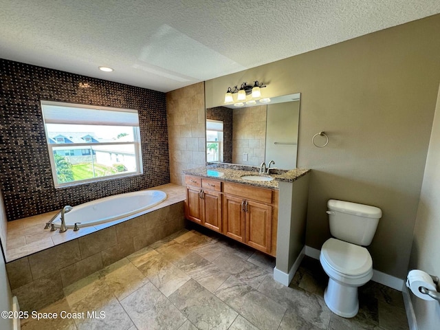 bathroom with a textured ceiling, a garden tub, vanity, and toilet