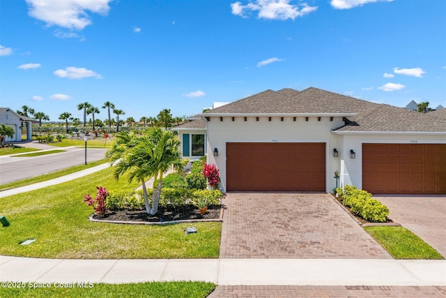 ranch-style house with a garage, stucco siding, a front yard, and decorative driveway