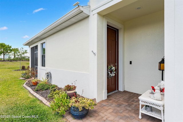 property entrance with stucco siding and a yard