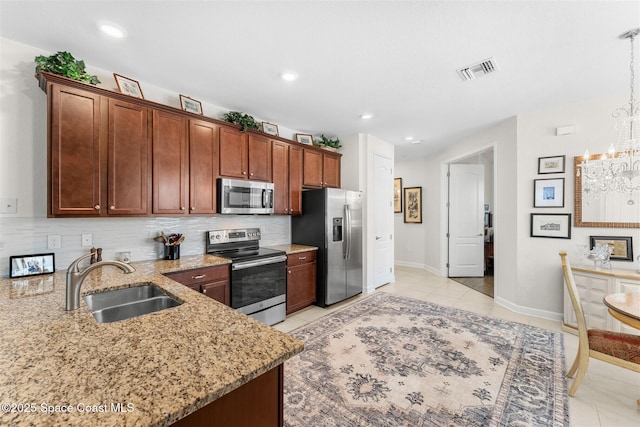 kitchen featuring light stone countertops, a sink, tasteful backsplash, visible vents, and appliances with stainless steel finishes