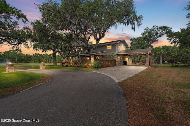800 Hidden Oaks Ln, Oak Hill, FL 32759 - view of front facade with a carport, driveway, stone siding, a lawn, and stucco siding