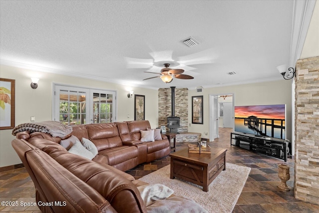 800 Hidden Oaks Ln, Oak Hill, FL 32759 - living room with a wood stove, visible vents, stone finish floor, and ornamental molding