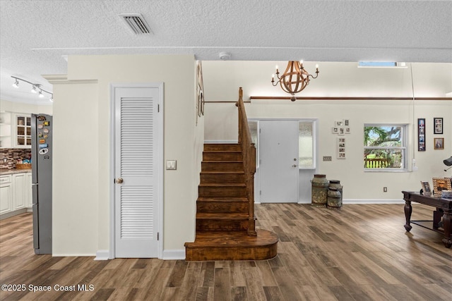 800 Hidden Oaks Ln, Oak Hill, FL 32759 - staircase with a textured ceiling, visible vents, a notable chandelier, wood finished floors, and track lighting