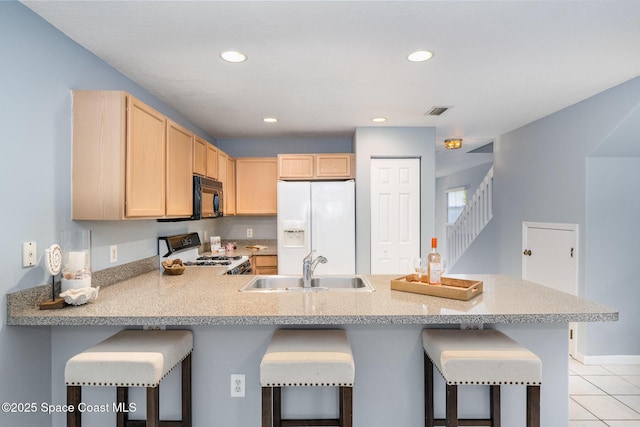 kitchen with white appliances, light brown cabinets, a sink, a peninsula, and recessed lighting