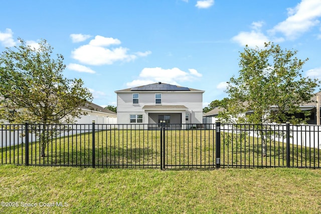 view of front facade with roof mounted solar panels, a fenced backyard, and a front yard