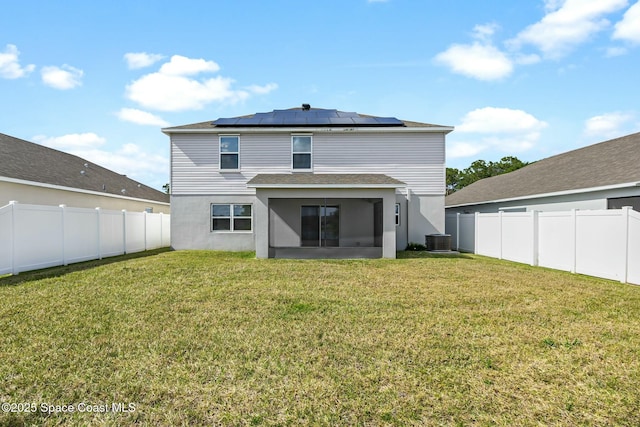 back of house with a lawn, roof mounted solar panels, a sunroom, and a fenced backyard