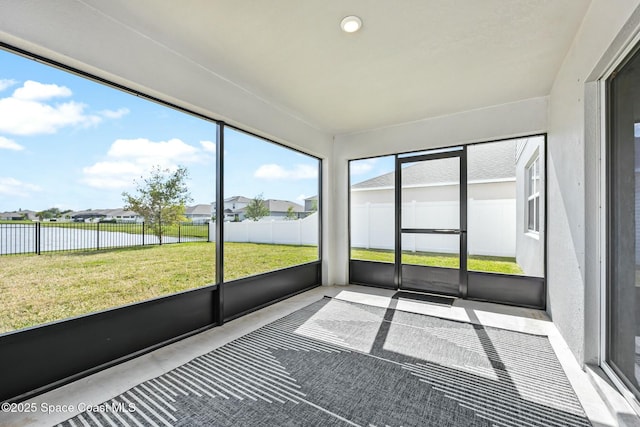 unfurnished sunroom with a residential view and a water view