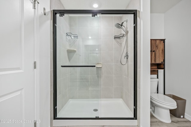 bathroom featuring baseboards, a shower stall, and toilet