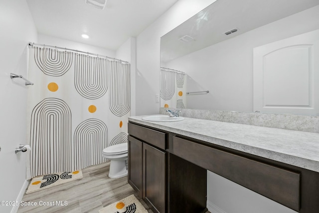 bathroom featuring wood finished floors, visible vents, vanity, and toilet