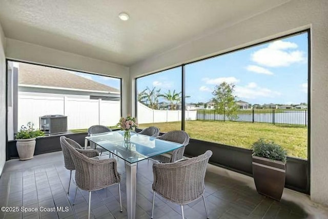 sunroom / solarium featuring outdoor dining area and a water view