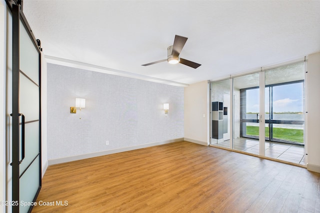300 S Sykes Creek Pkwy Unit 106, Merritt Island, FL 32952 - empty room with floor to ceiling windows, ceiling fan, light wood-type flooring, baseboards, and a water view