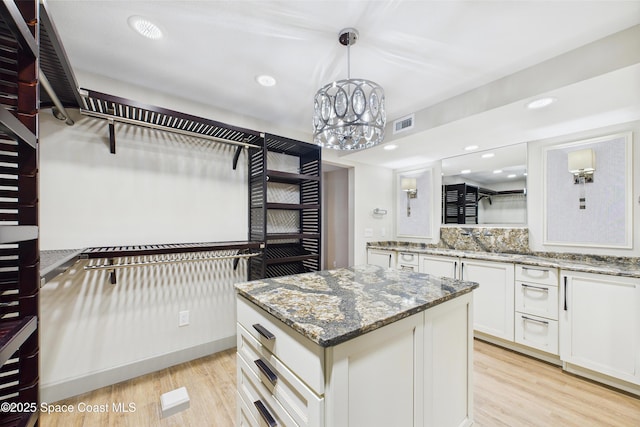 300 S Sykes Creek Pkwy Unit 106, Merritt Island, FL 32952 - kitchen with a notable chandelier, light wood-style floors, white cabinetry, a kitchen island, and pendant lighting