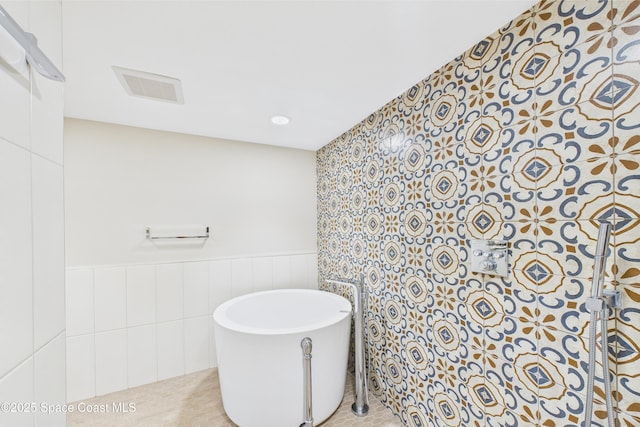300 S Sykes Creek Pkwy Unit 106, Merritt Island, FL 32952 - bathroom featuring visible vents, a wainscoted wall, and a soaking tub