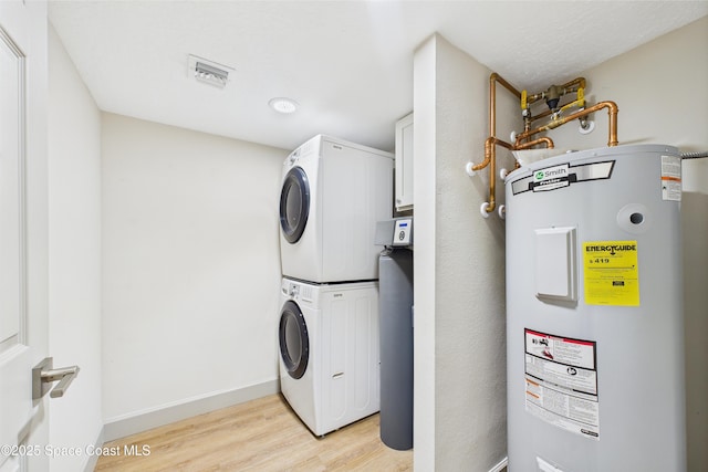300 S Sykes Creek Pkwy Unit 106, Merritt Island, FL 32952 - washroom featuring stacked washer and dryer, baseboards, light wood-type flooring, visible vents, and electric water heater