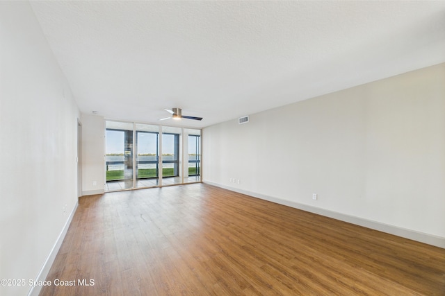 300 S Sykes Creek Pkwy Unit 106, Merritt Island, FL 32952 - spare room featuring a ceiling fan, baseboards, wood finished floors, visible vents, and expansive windows