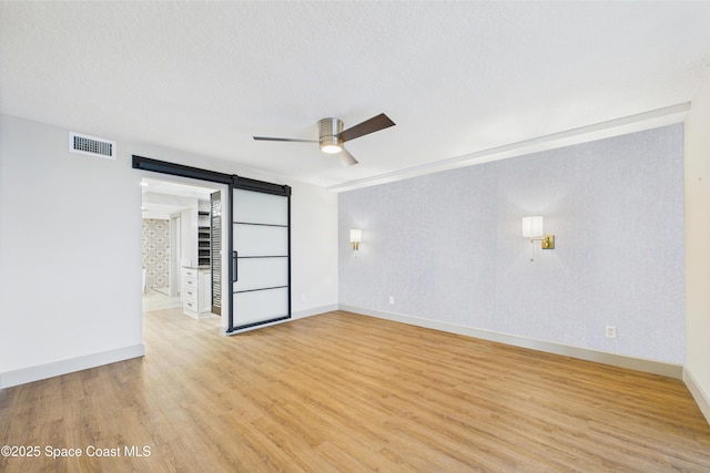 300 S Sykes Creek Pkwy Unit 106, Merritt Island, FL 32952 - empty room with a ceiling fan, visible vents, a barn door, and light wood-style floors
