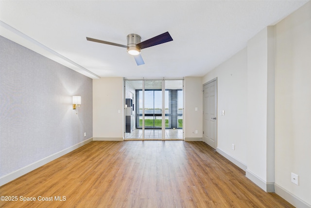 300 S Sykes Creek Pkwy Unit 106, Merritt Island, FL 32952 - unfurnished room featuring a ceiling fan, baseboards, expansive windows, and light wood-style flooring
