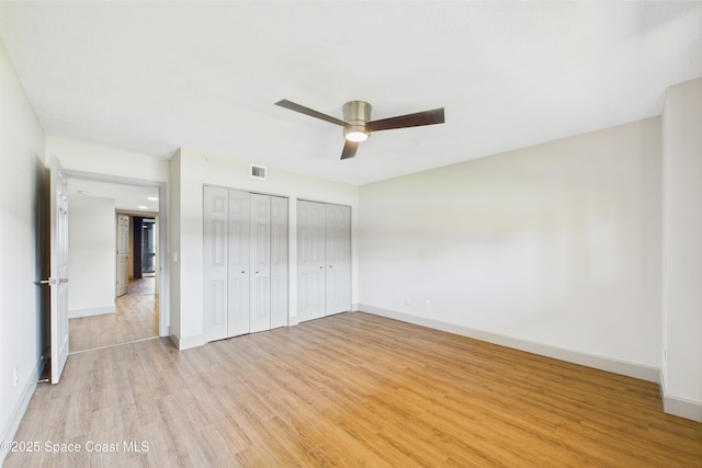 300 S Sykes Creek Pkwy Unit 106, Merritt Island, FL 32952 - unfurnished bedroom featuring a ceiling fan, visible vents, light wood-type flooring, baseboards, and two closets