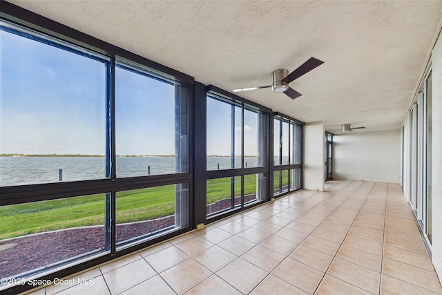 300 S Sykes Creek Pkwy Unit 106, Merritt Island, FL 32952 - unfurnished sunroom with a wall of windows, tile patterned flooring, a textured ceiling, a ceiling fan, and a water view