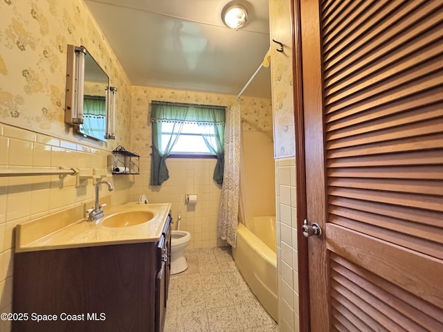690 Lemon Grove Ave, Melbourne, FL 32904 - full bathroom with wallpapered walls, wainscoting, vanity, tile walls, and shower / tub combo