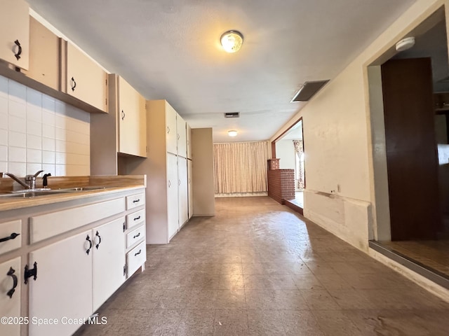 690 Lemon Grove Ave, Melbourne, FL 32904 - kitchen with light countertops, decorative backsplash, and white cabinetry