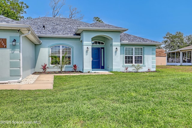 1307 Lotus St SE, Palm Bay, FL 32909 - view of front of house featuring stucco siding, a front lawn, and roof with shingles