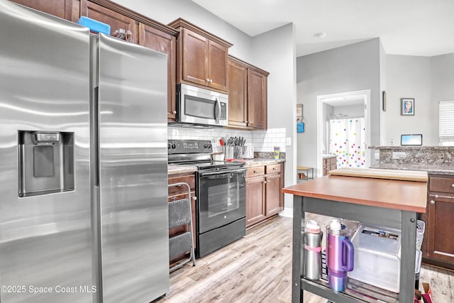 1307 Lotus St SE, Palm Bay, FL 32909 - kitchen with appliances with stainless steel finishes, light wood-type flooring, tasteful backsplash, and brown cabinets