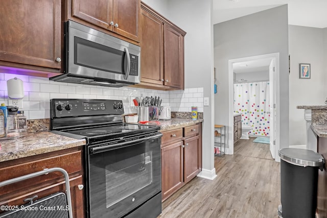 1307 Lotus St SE, Palm Bay, FL 32909 - kitchen featuring black electric range oven, stainless steel microwave, light wood-style floors, tasteful backsplash, and baseboards