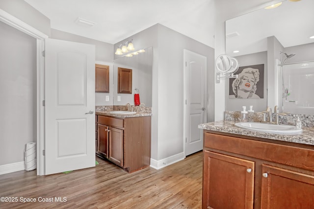 1307 Lotus St SE, Palm Bay, FL 32909 - bathroom featuring wood finished floors, baseboards, two vanities, and a shower