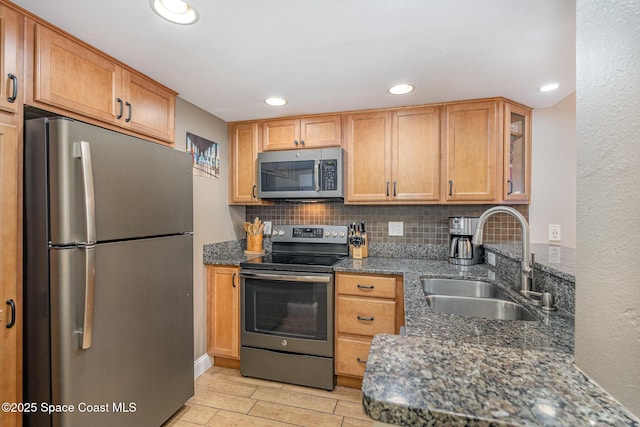 5350 Ocean Beach Blvd Unit 212, Cocoa Beach, FL 32931 - kitchen featuring stainless steel appliances, dark stone countertops, backsplash, a sink, and light wood-style floors